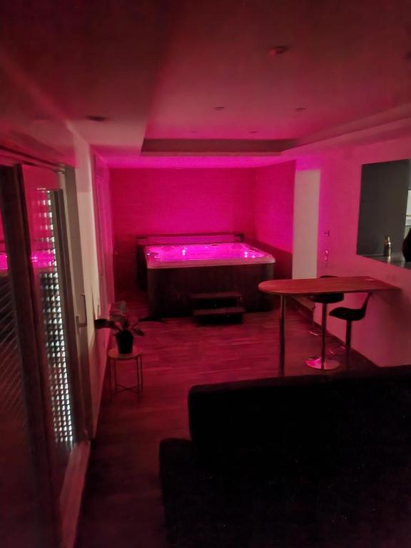 une chambre avec baignoire dans une chambre avec des lumières roses dans l'établissement La belle étoile, 