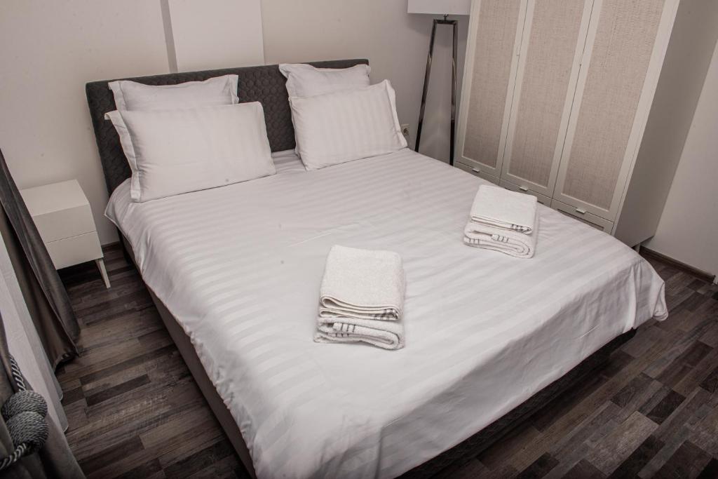 a bed with white sheets and towels on it at Maria's Premium Suite in Baia Mare