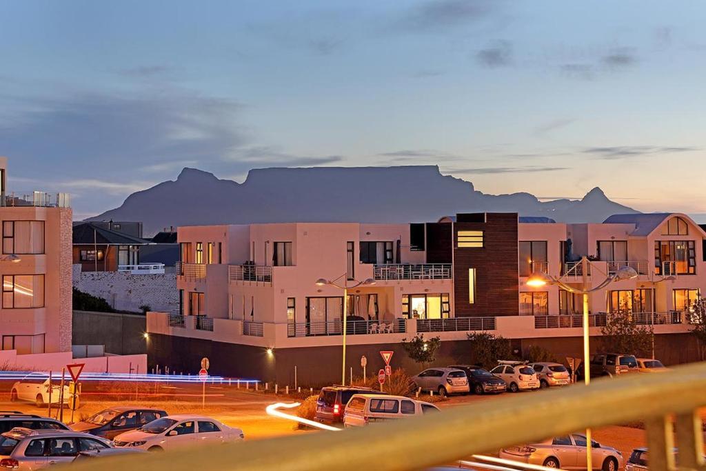 um parque de estacionamento com carros estacionados em frente aos edifícios em Eden On The Bay 108 by HostAgents em Bloubergstrand