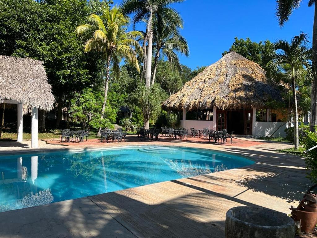 a resort with a swimming pool and a thatch hut at La casita maya, Valladolid in Valladolid