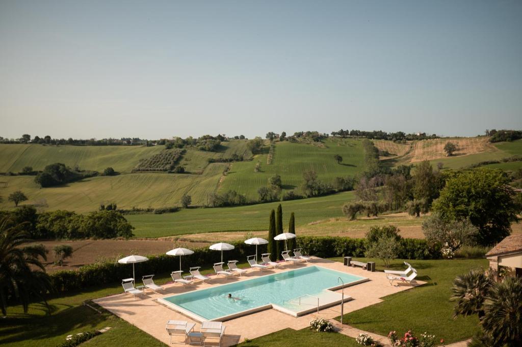 einen Luftblick auf einen Pool mit Sonnenschirmen in der Unterkunft Poggio Antico in Monte San Vito