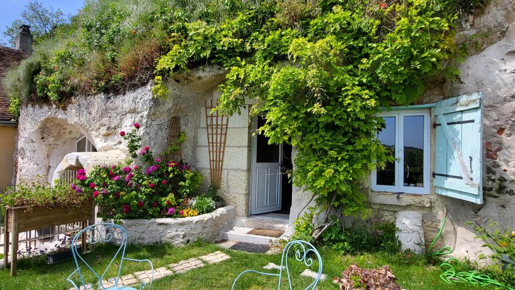 uma casa de pedra com uma janela e flores em Troglogîtes de la Tourette em Les Roches-lʼÉvêque