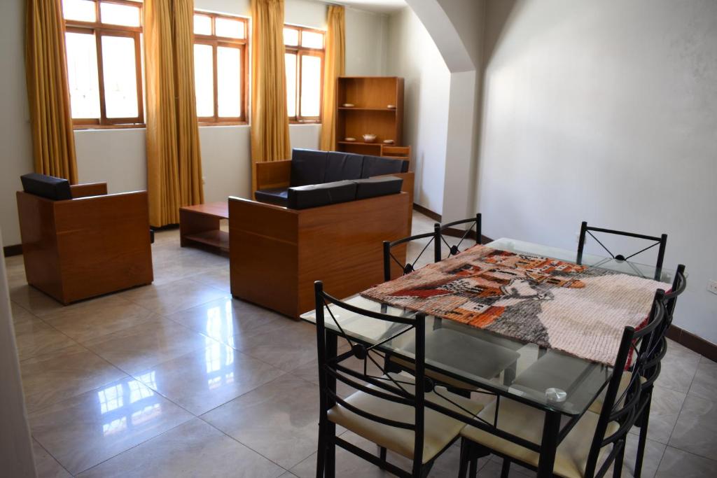 um quarto com uma mesa, cadeiras e janelas em Casa a 3 cuadras de la plaza de armas Huamanga em Ayacucho