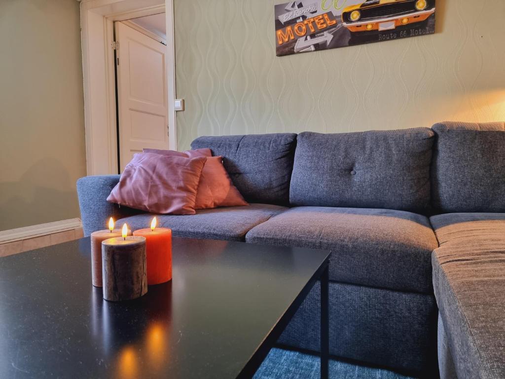 Sala de estar con sofá y mesa con 2 velas en Kjellerleilighet egen inngang., en Stange