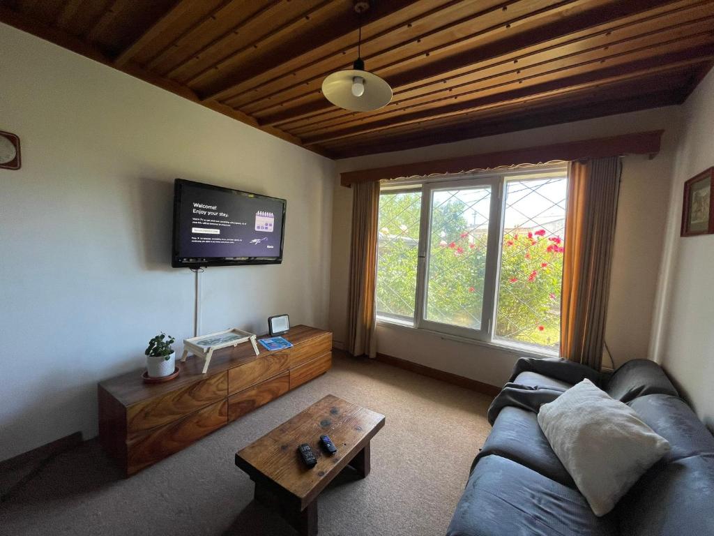 Hermosa casa zona céntrica Bariloche في سان كارلوس دي باريلوتشي: غرفة معيشة مع أريكة وتلفزيون بشاشة مسطحة