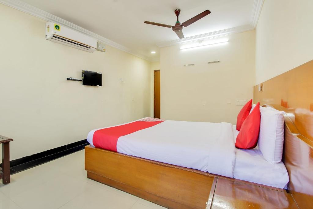 a bedroom with a bed with red and white pillows at OYO Srinivasa Residency in Tirupati