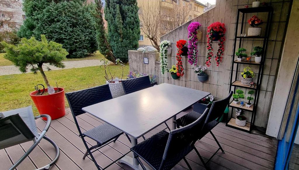einen Tisch und Stühle auf einer Terrasse mit Pflanzen in der Unterkunft Appartement avec terrasse in Sion