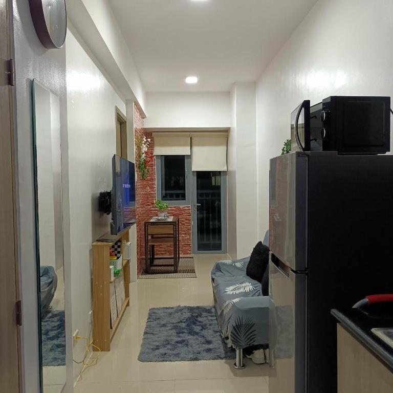 uma sala de estar com uma televisão, um sofá e um frigorífico em 1BR Aesthetic Condotel with Balcony - EDSA em Manila