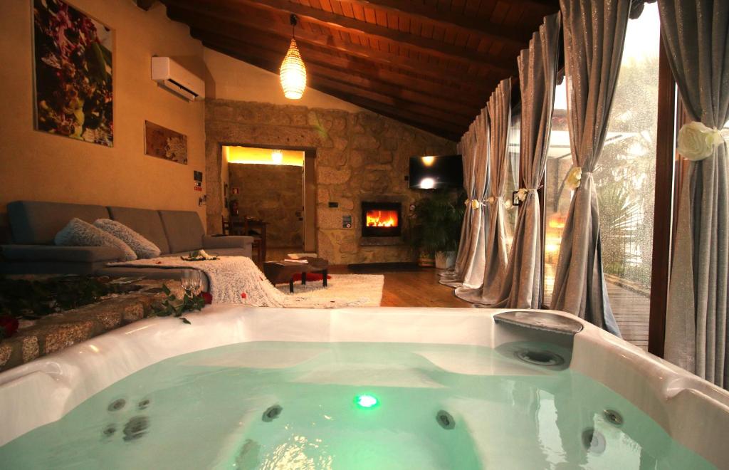 une grande baignoire dans une pièce avec un salon dans l'établissement Casa Favo de Mel - Jacuzzi Privado & Lareira - Piscina, à Arcos de Valdevez