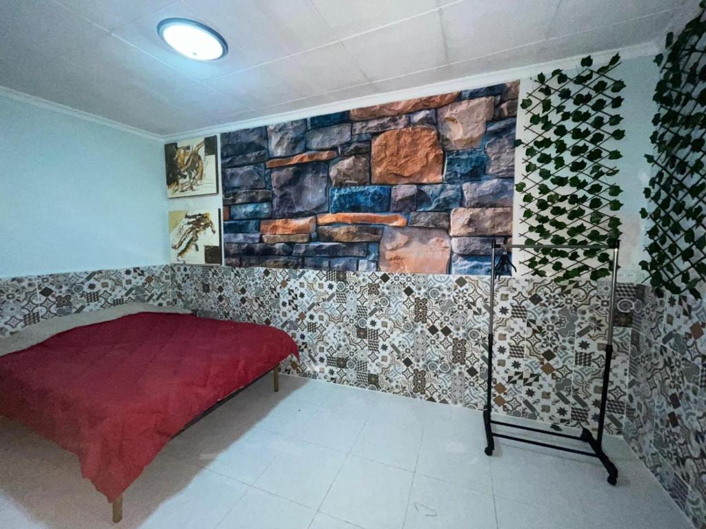 een kamer met een rode bank en een stenen muur bij Amplia habitación céntrica in Cartagena