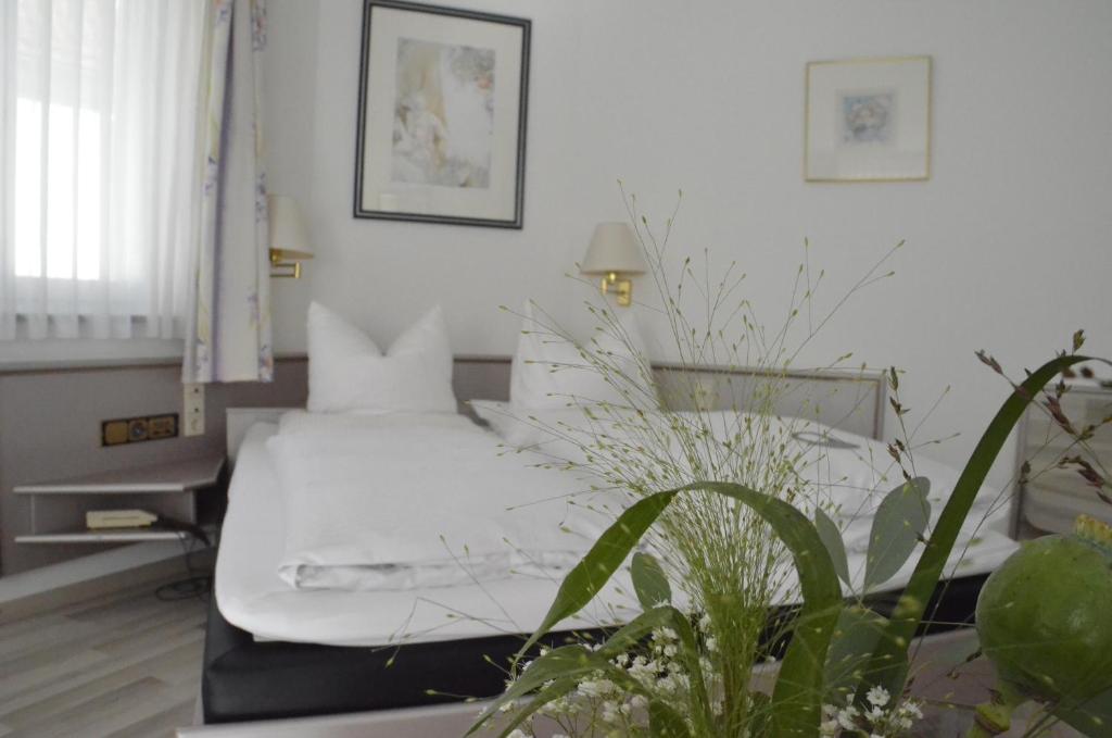 a bedroom with a bed with white sheets and a plant at Boardinghaus zu Coburg in Coburg