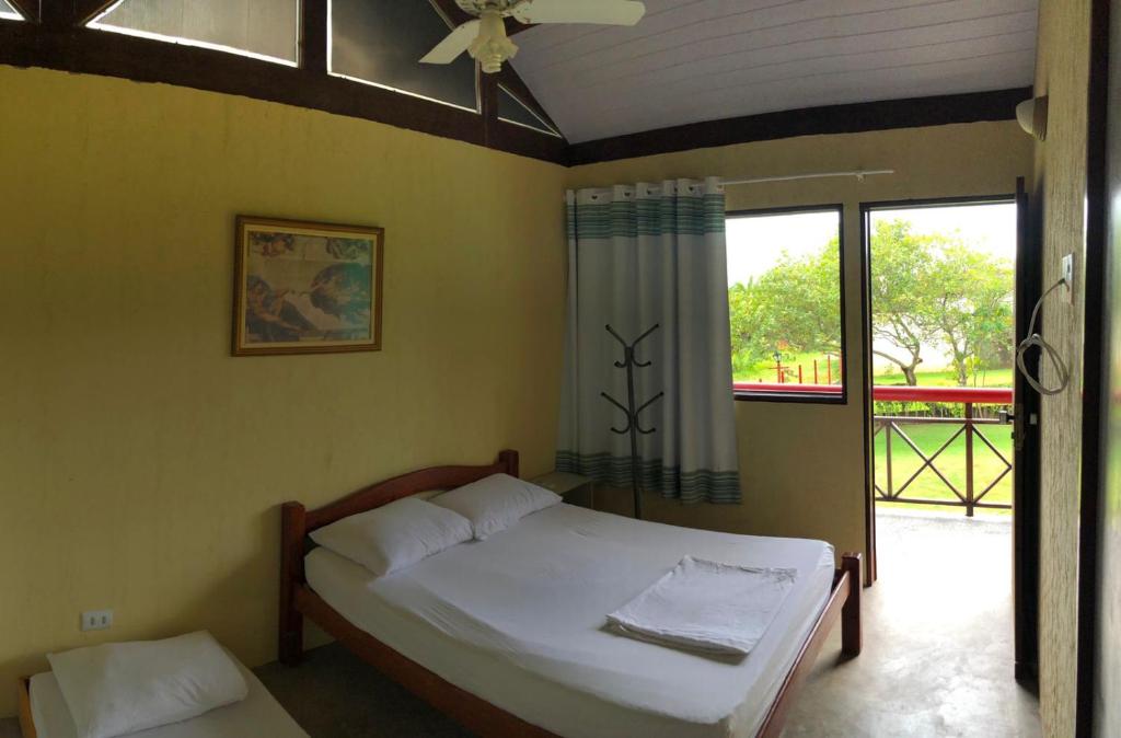 a bedroom with a bed and a large window at Chalé Verde in Tamandaré