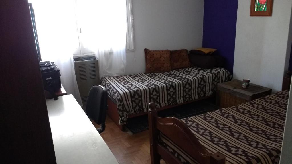 マル・デル・プラタにあるHabitación privada en Casa Musical Iのベッド1台とソファが備わる小さな客室です。