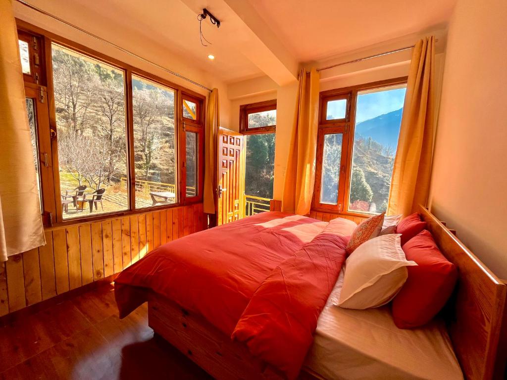 une chambre avec un lit dans une pièce avec des fenêtres dans l'établissement Flüstern Homestay, à Nagar