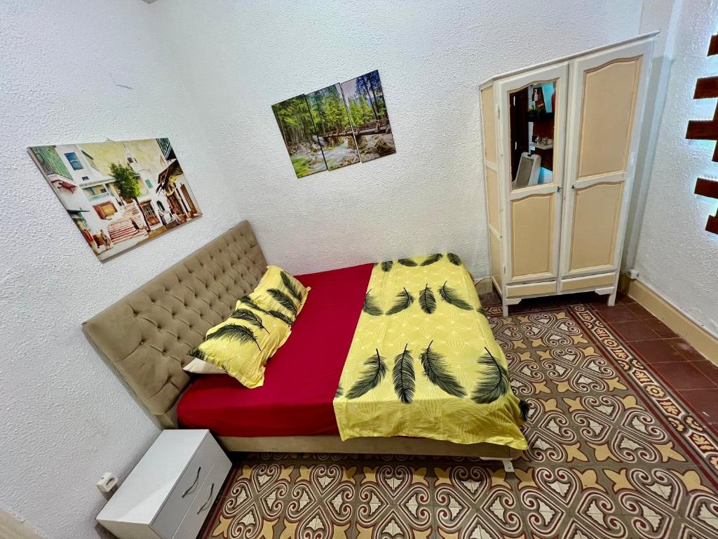 Dormitorio pequeño con cama con manta roja y amarilla en Un studio au centre ville de Tunis en Túnez