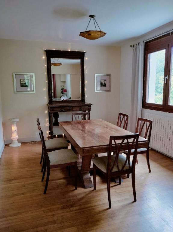 a dining room with a table and chairs and a mirror at Les Beaux Sapins 2 in Rochechouart
