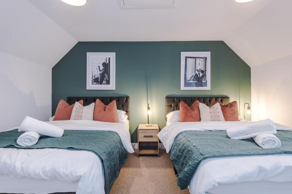 Beautiful Stoke Home Sleeps 10 by PureStay Short Lets في ستوك أون ترينت: غرفة نوم بسريرين وجدار أخضر