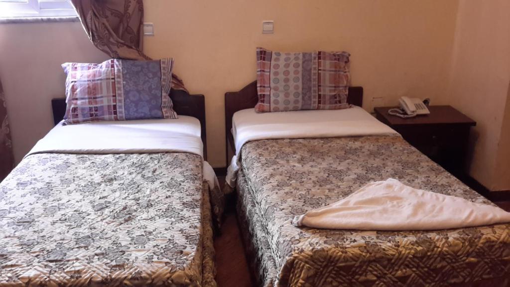 two beds in a small room with a phone at 70 Dereja Hotel in Addis Ababa