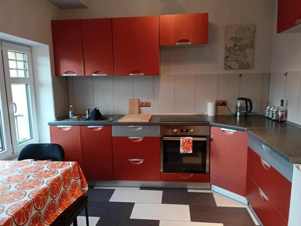 a kitchen with red cabinets and a stove top oven at Lemuria Przytulny pokój Chojnowska in Legnica