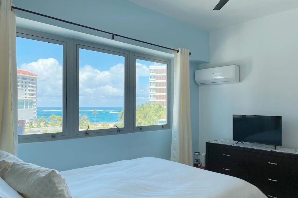 - une chambre avec un lit et une grande fenêtre dans l'établissement soundproof windows over Condado Beach, San Juan apts, à San Juan