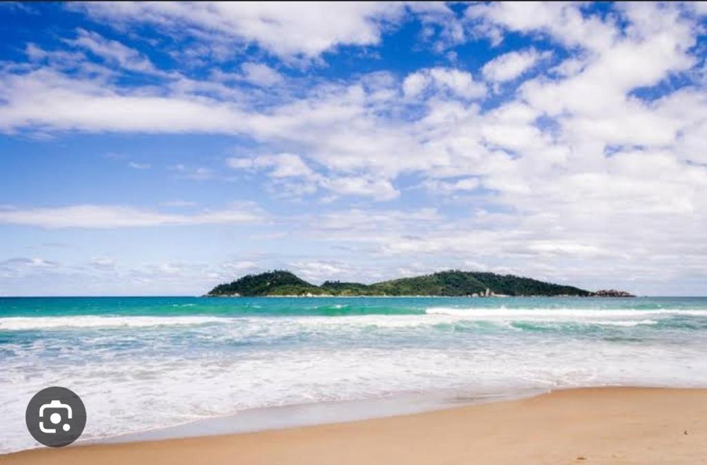 una playa vacía con una isla en el océano en Ap a 6km do aeroporto Floripa en Florianópolis