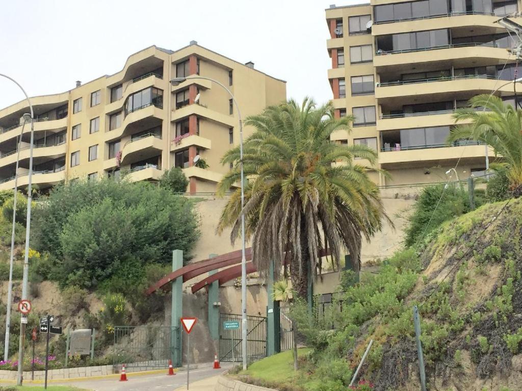 a building with a palm tree next to a street at Calafquen Viña del mar in Viña del Mar