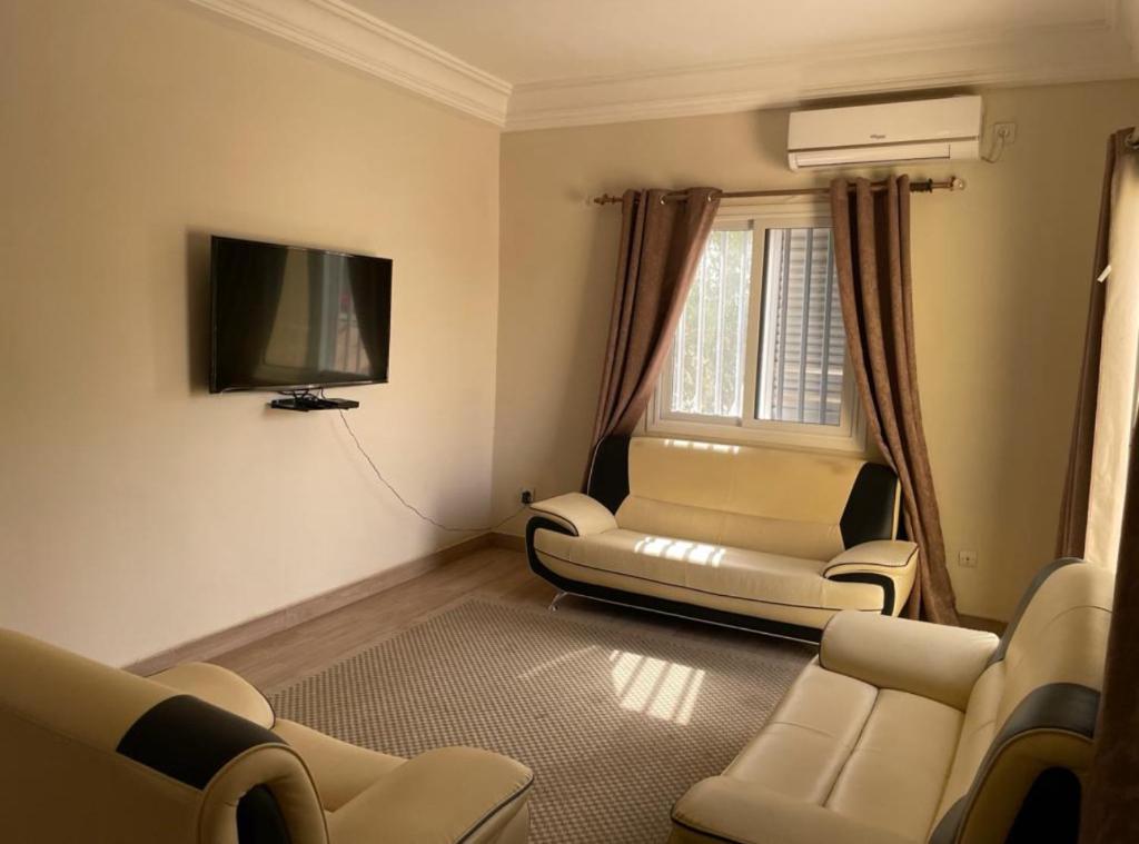 sala de estar con sillas y TV de pantalla plana en Superbe 2pieces avec climatisation en Fatick