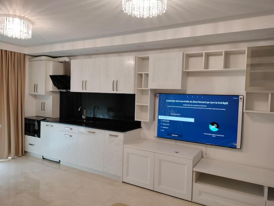een keuken met witte kasten en een flatscreen-tv bij Nina Studio Sibiu in Cisnădie