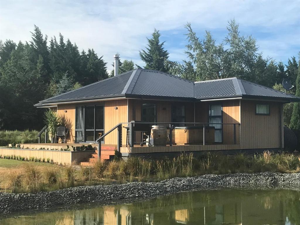 une grande maison avec une grande terrasse à côté d'un étang dans l'établissement Woodbank Road Escape, à Hanmer Springs