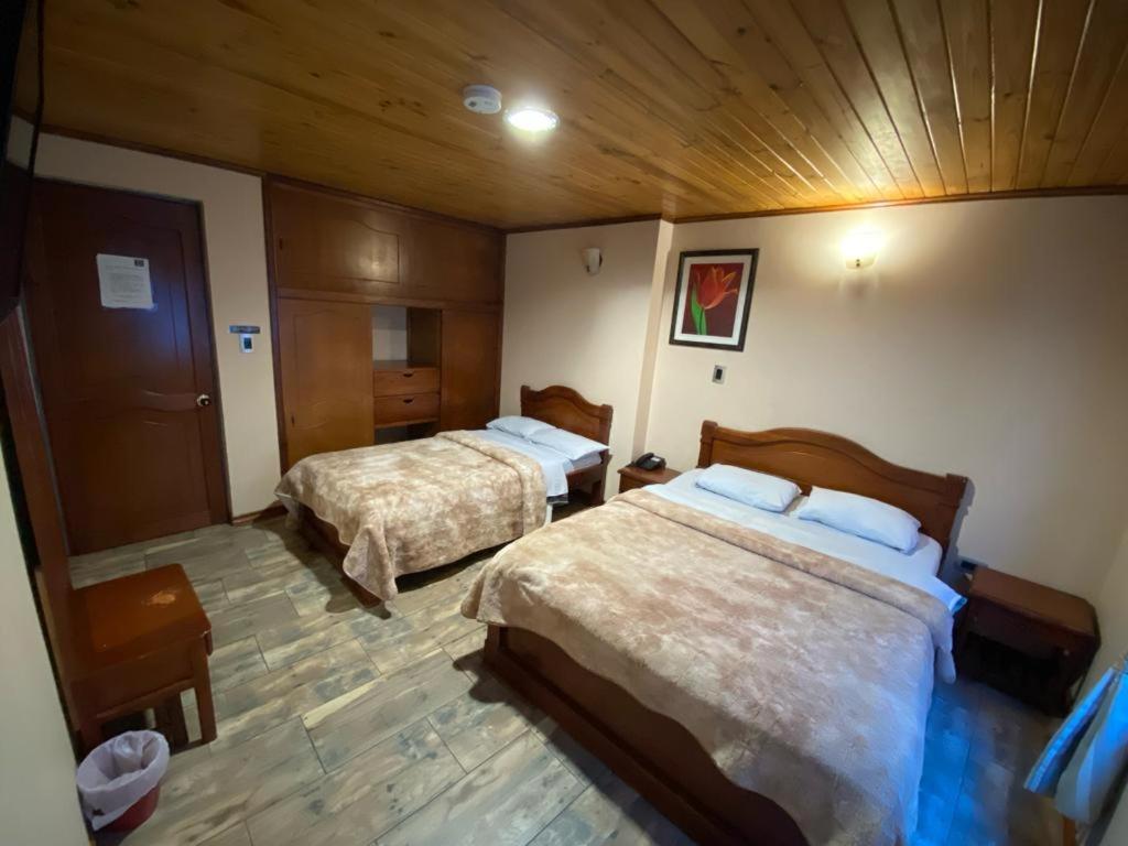 a bedroom with two beds and a wooden ceiling at Hotel Buenaventura in Pasto