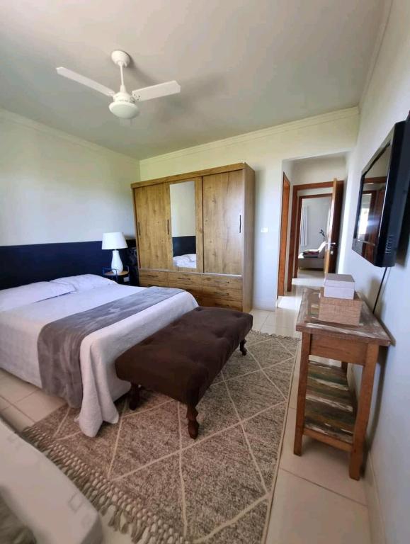 a bedroom with a bed and a table and a television at Casa do Renato in Anchieta