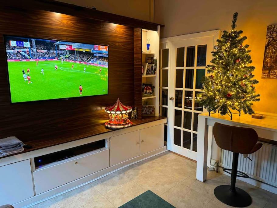 a living room with a television and a christmas tree at Warm family home close to City Centre (4bed) in Manchester