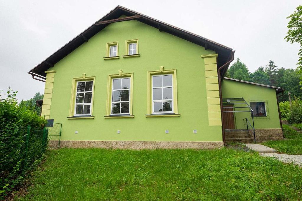 une maison verte avec des fenêtres au-dessus d'une cour dans l'établissement Turistická chata Nesnídalka, 