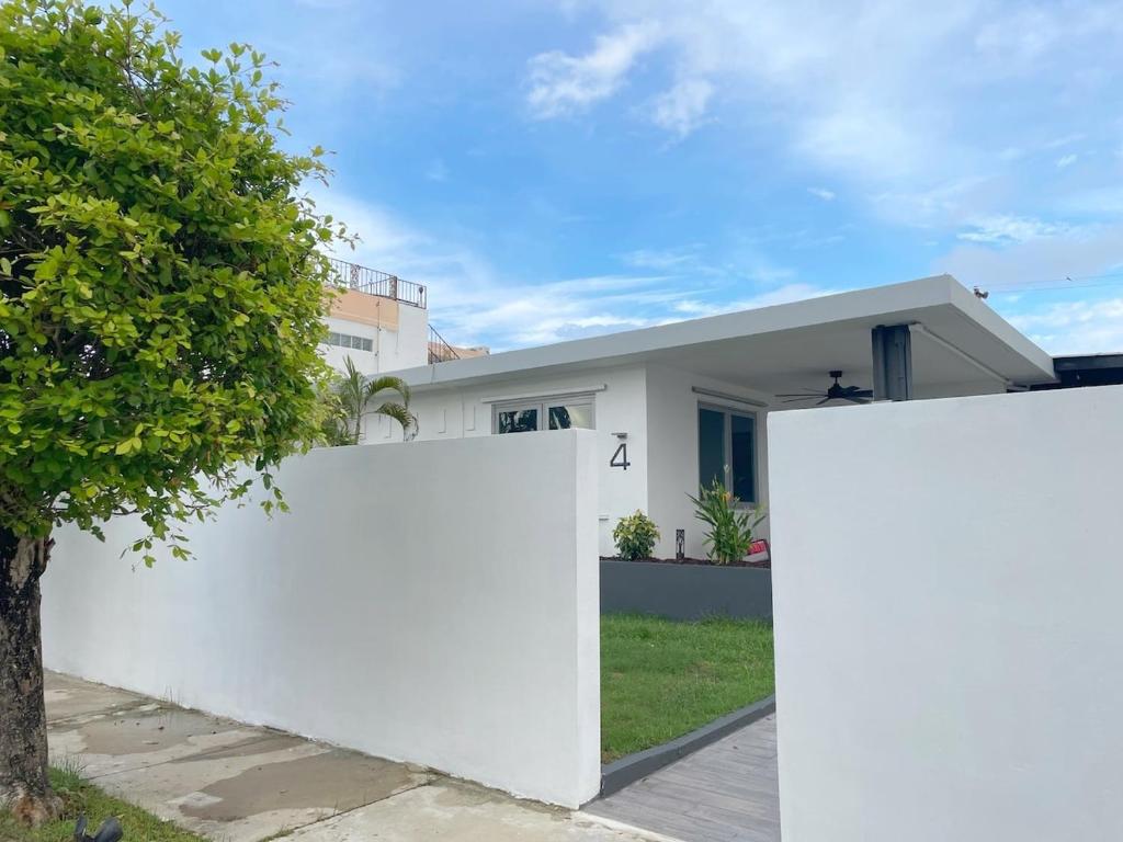 a white fence in front of a white house at Pool House by Isla Verde Beach home in San Juan