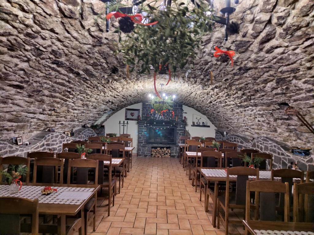 Habitación con mesas, sillas y pared de piedra. en Pivnica a Penzion pri studni en Detva