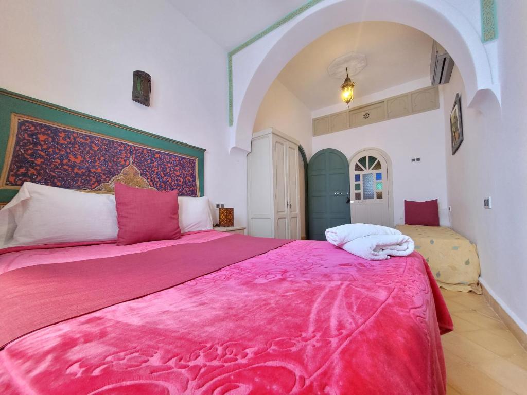 a bedroom with a large bed with a pink blanket at Honey Suckle in Chefchaouene