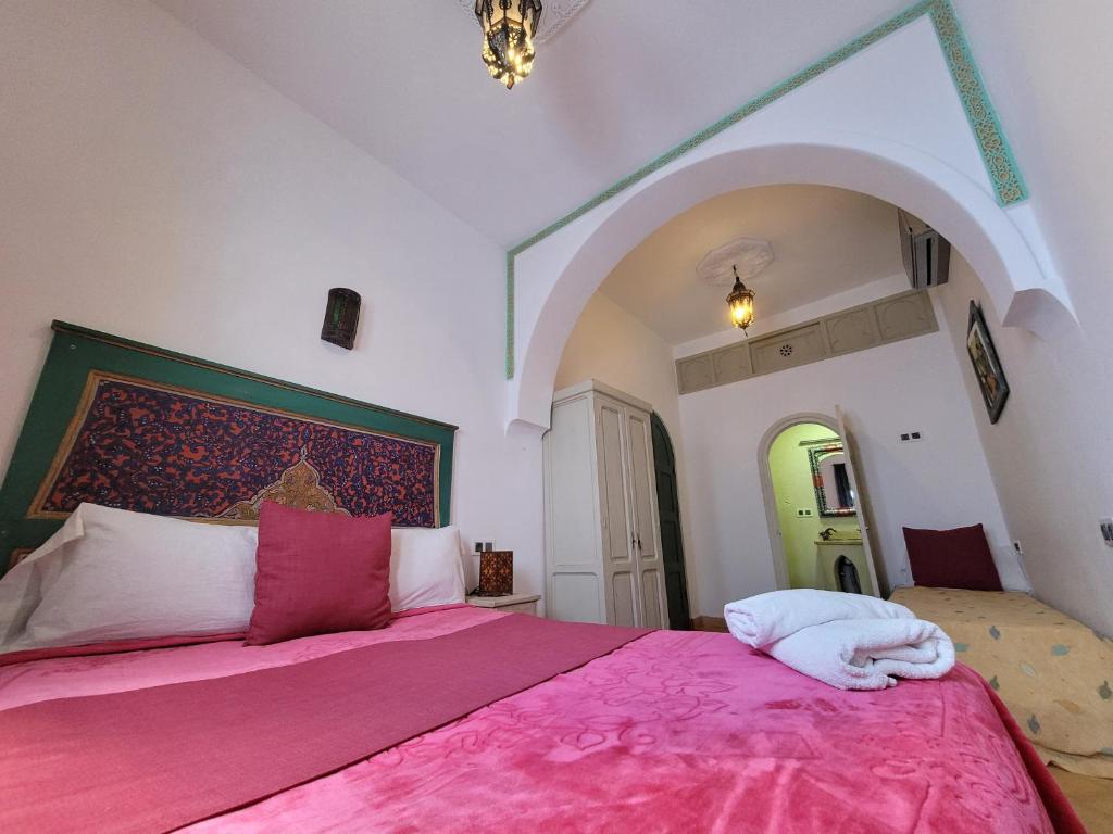 a bedroom with a pink bed with a pink blanket at Honey Suckle in Chefchaouene
