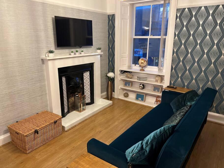 a living room with a blue couch and a fireplace at Harris Apartment in Montrose