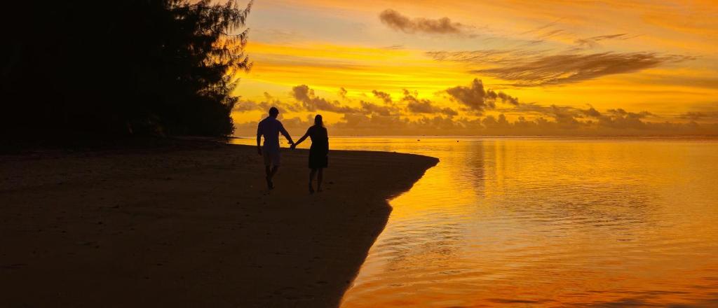 two people walking on the beach at sunset at Resort Tava'e in Amuri