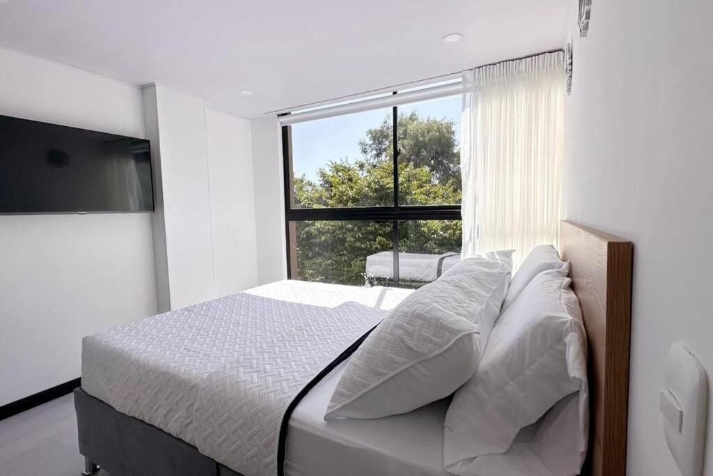een slaapkamer met een bed en een groot raam bij Movistar arena 302 in Bogota