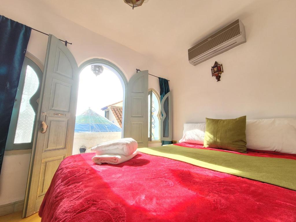 a bedroom with a large bed with a red blanket at Honey Suckle in Chefchaouene
