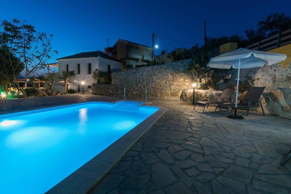 a swimming pool at night with an umbrella and chairs at Gavalochori Stone House in Gavalochori
