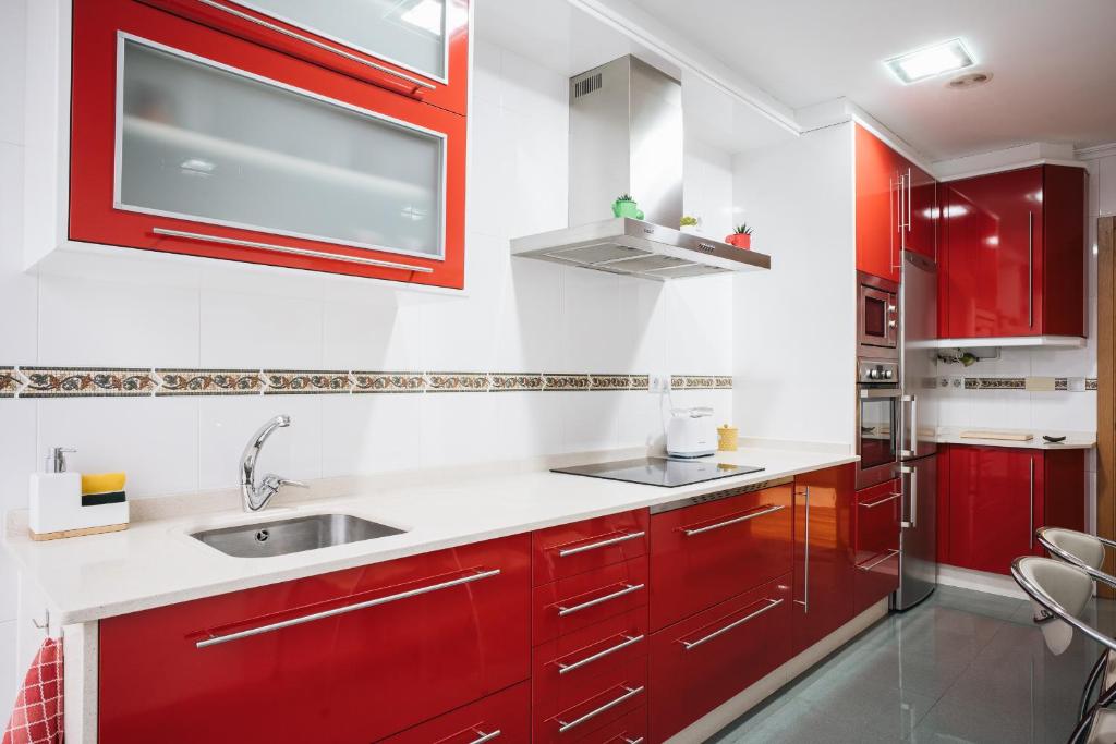 a kitchen with red cabinets and a sink at Casa Losada in Monforte de Lemos