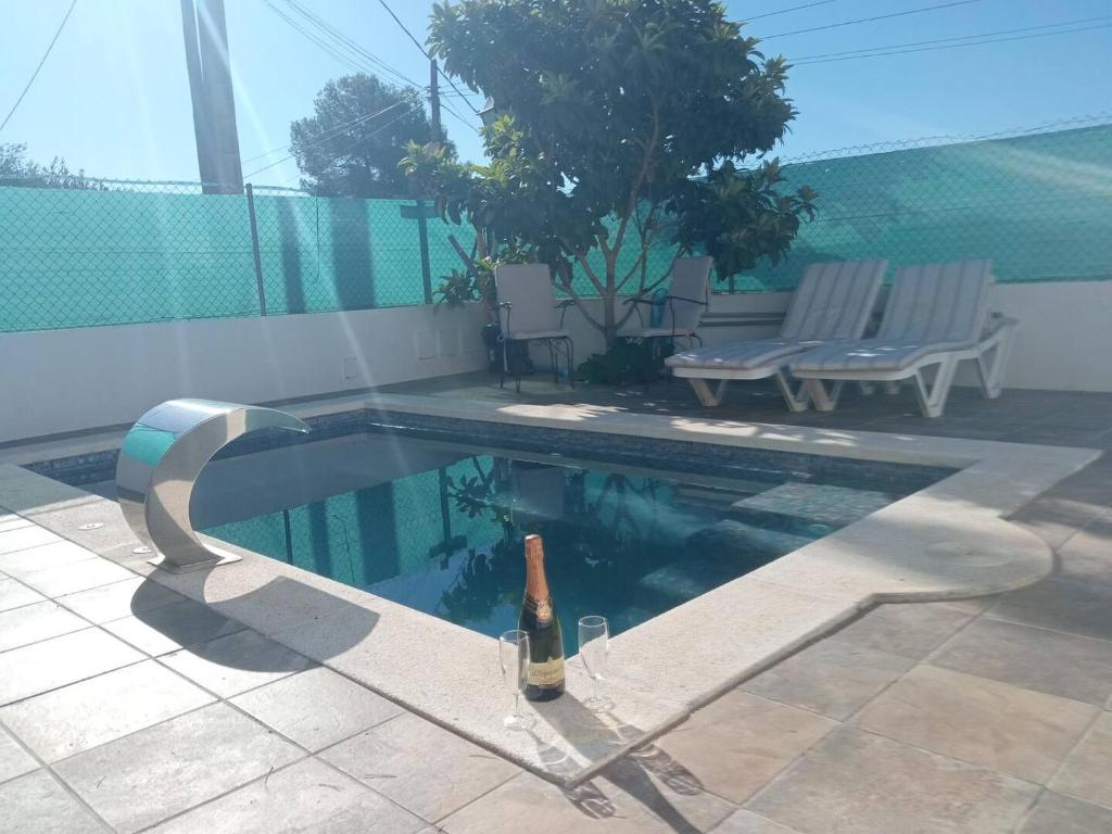 - une bouteille de vin assise sur une chaise près de la piscine dans l'établissement Els Rosers - con jacuzzy XL y barbacoa, à Rodonyà