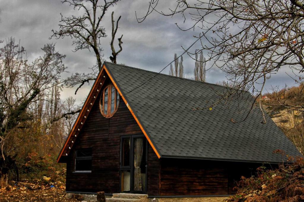 una pequeña casa con techo negro en Katskhi Cottage, Your Cozy Stay en Katsʼkhi