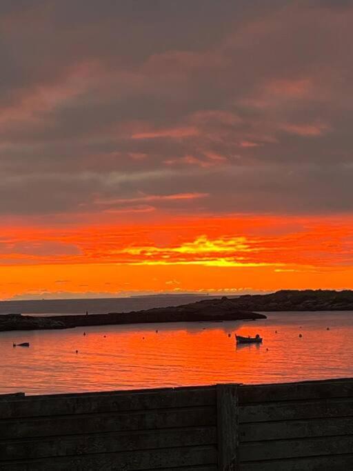 un coucher de soleil sur l'océan avec des bateaux dans l'eau dans l'établissement Maison face aux îles de Melon, Molène et Ouessant 6P, à Porspoder