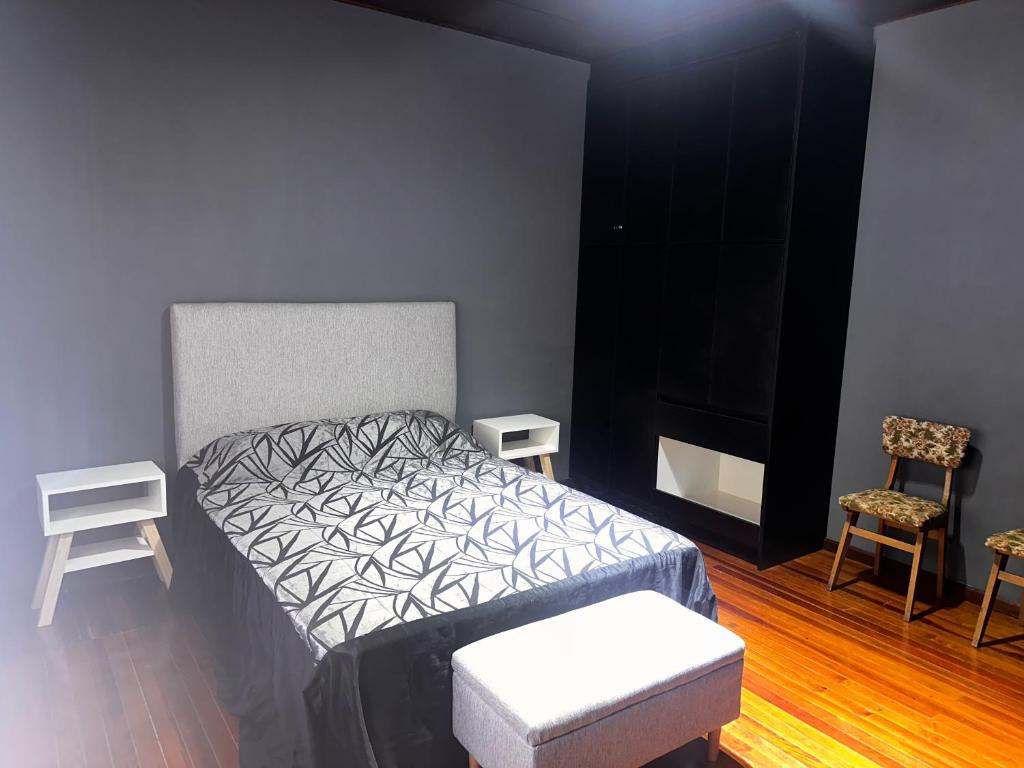 ein Schlafzimmer mit einem Bett, einem Stuhl und einem TV in der Unterkunft Quinta Mitre in San Nicolás de los Arroyos