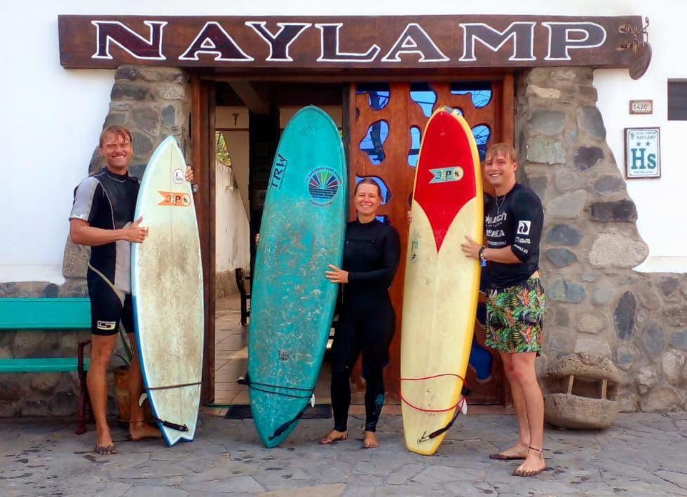 萬查科的住宿－Hostal Naylamp，一群人站在一个装有冲浪板的商店前