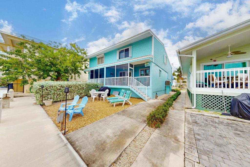 a blue house with chairs and a patio at Canalside at KCB in Key Colony Beach