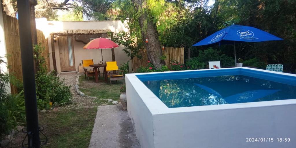 a swimming pool in a backyard with an umbrella at Monoambiente Golondrina in Capilla del Monte